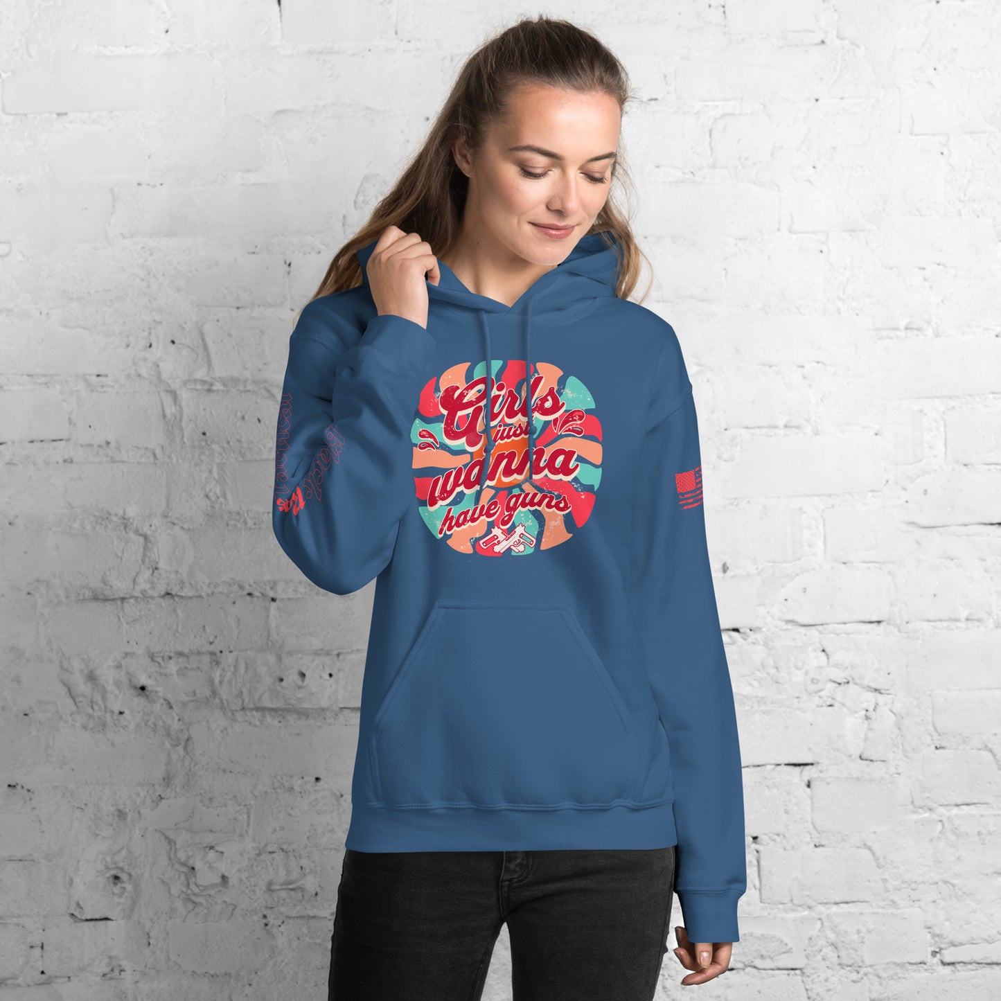 Person wearing a blue hoodie with colorful graphic design against a white brick wall.