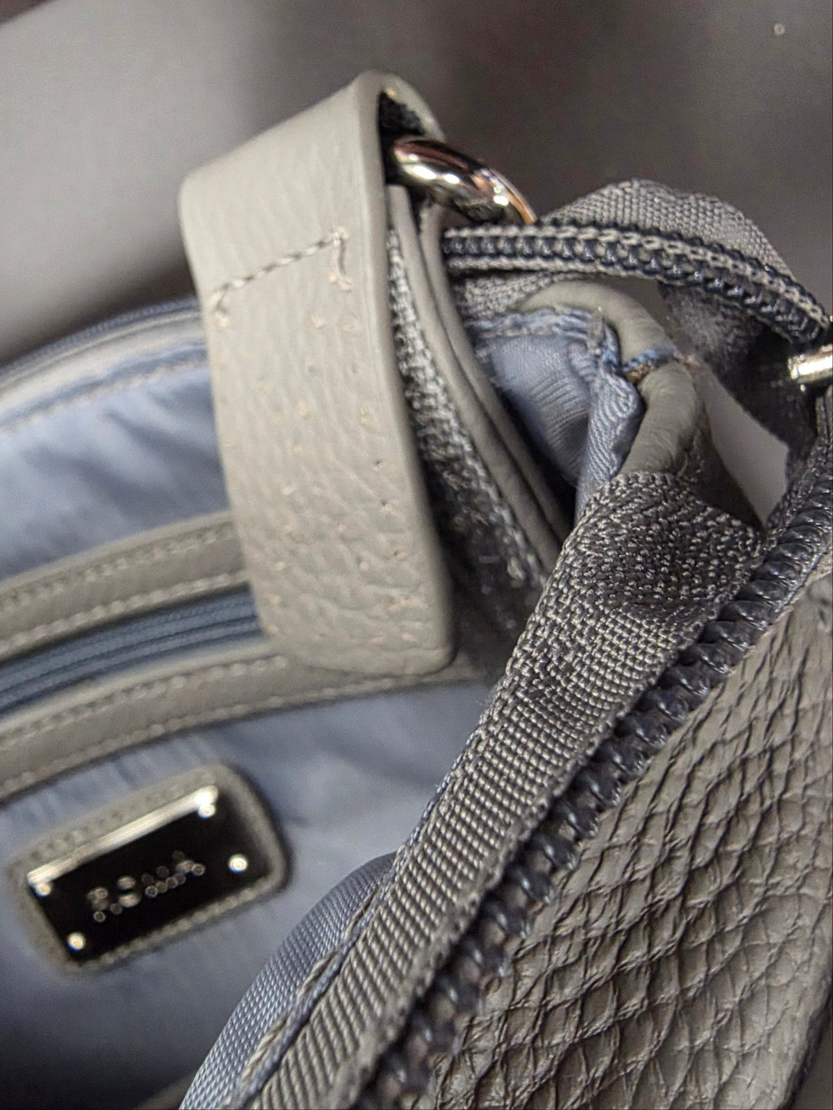 Gray purse showing where thread has come undone