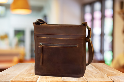 Brown leather bag on a wooden table with a blurred indoor background