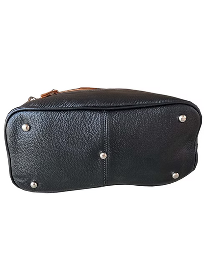 Black pebbled leather bag base showing silver-tone metal studs and a small portion of a brown leather zipper pull on a white background.