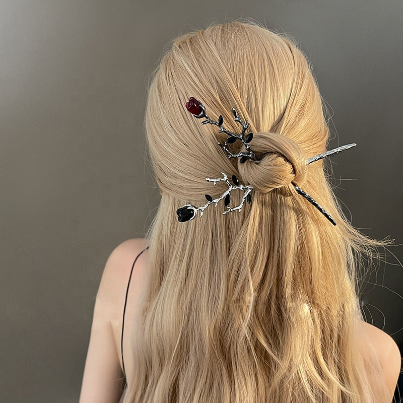 Red and black metal rose hair sticks with thorned branch design shown in women's hair