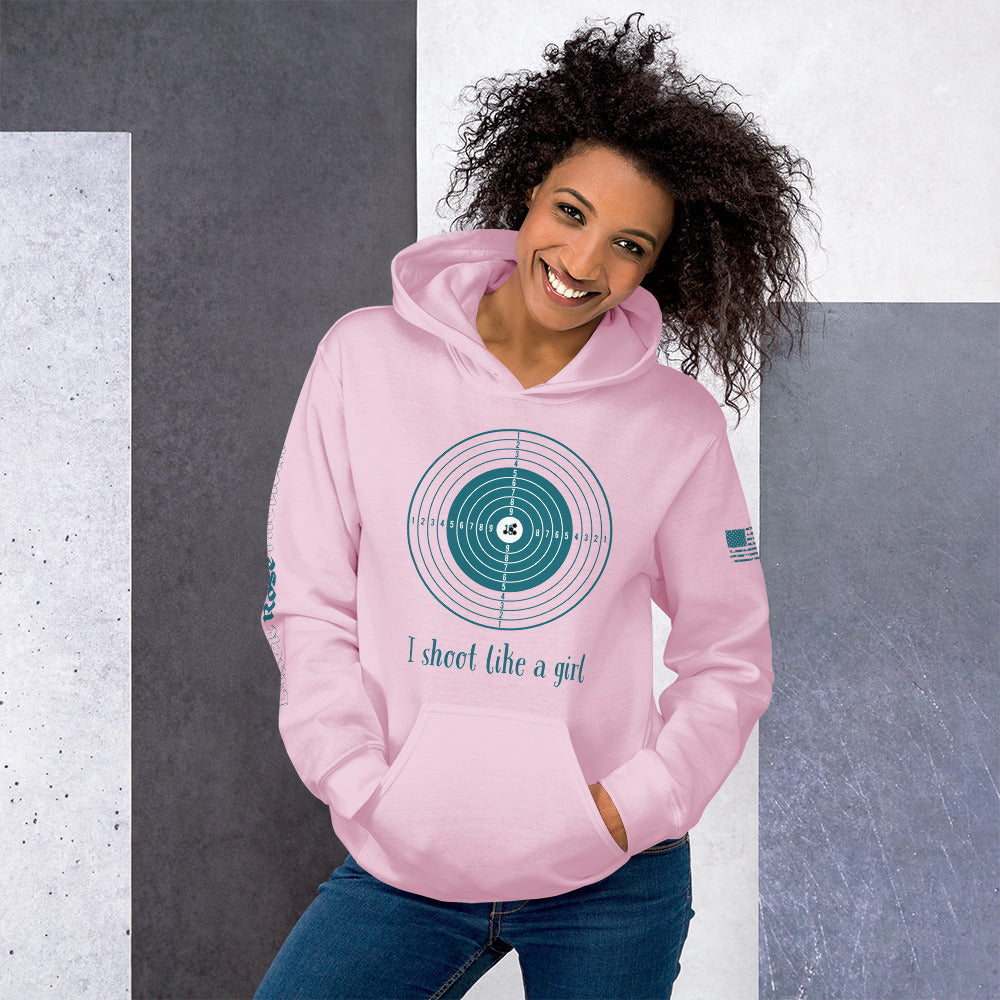 Woman wearing a pink hoodie with a graphic design and text, standing against a gray and white background.
