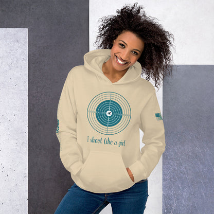 Woman wearing a beige hoodie with a graphic design and text, standing against a gray and white background.